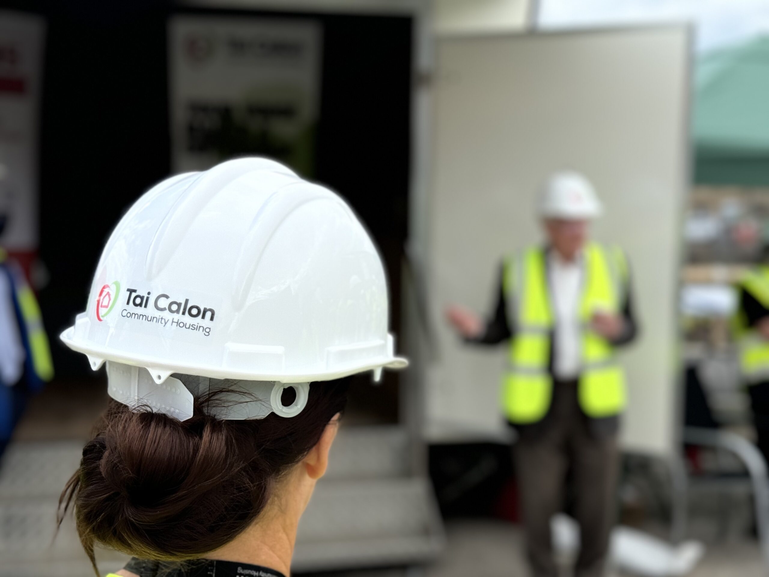 Tai Calon colleague listening to the Chair of the Board talking to the group of people